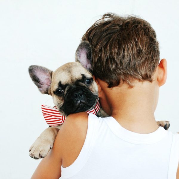 A boy carrying a brown dog